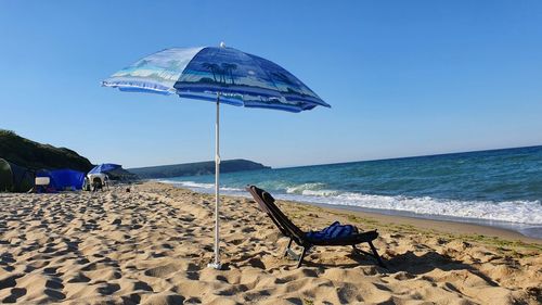 Deck chairs on beach against clear sky