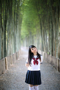 Portrait of smiling young woman standing against trees