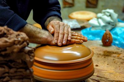 Midsection of potter working at pottery workshop