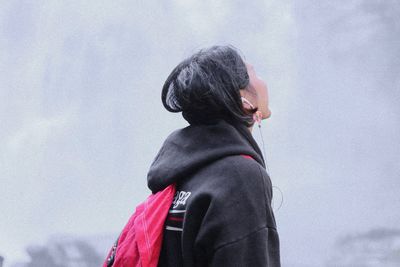 Rear view of woman standing against sky during winter