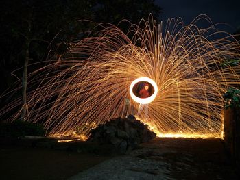 Young man spinning wire wool against sky at night