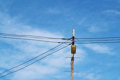 Low angle view of electricity pylon against blue sky