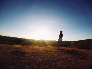 Rear view of woman standing on field against sky