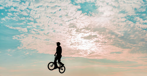 Freestyle cyclist practicing street bmx in backlight at sunset