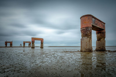 Wooden posts on beach against sky