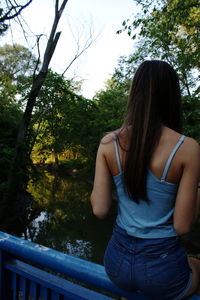 Rear view of woman standing against trees