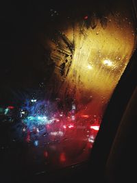Illuminated city seen through wet glass window