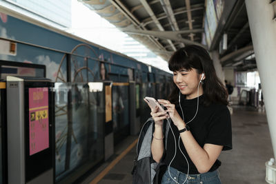 Young woman using mobile phone at railroad station