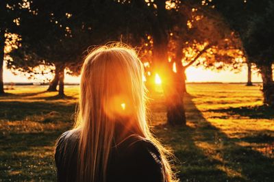 Rear view of woman on field during sunset