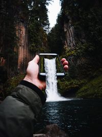 Midsection of person holding waterfall in forest