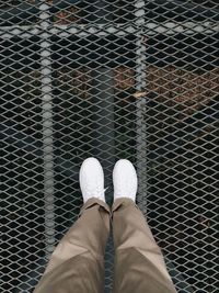 Low section of man standing on chainlink fence