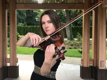 Portrait of young woman playing violin at park