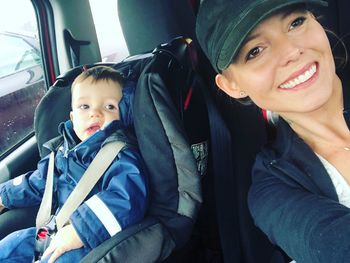 Portrait of smiling mother and child sitting in car