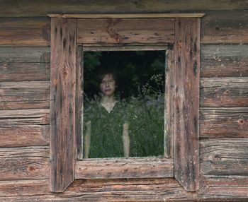 Portrait of boy looking through cottage window