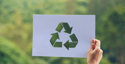 Midsection of person holding paper against blurred background