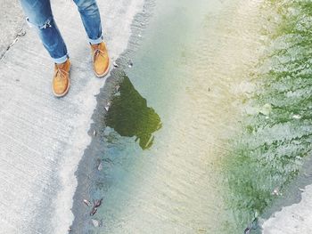 Low section of woman standing on wet sand