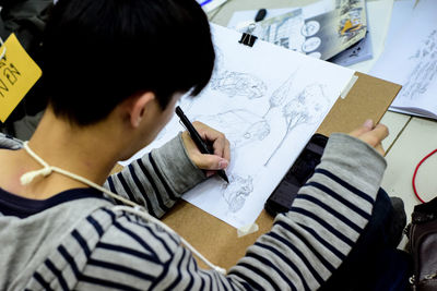 High angle view of teenage boy drawing on paper