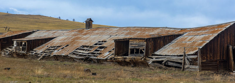 Exterior of abandoned house on field against sky