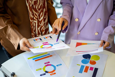 Midsection of business people working on table