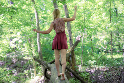 Young woman standing on tree in forest