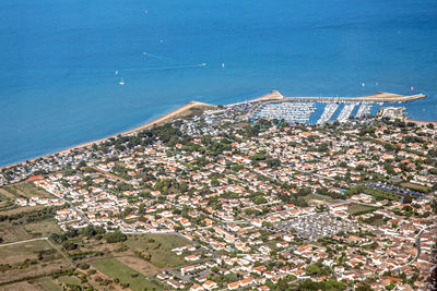 High angle view of townscape by sea against blue sky