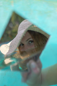 Close-up of young woman holding mirror with reflection in wading pool