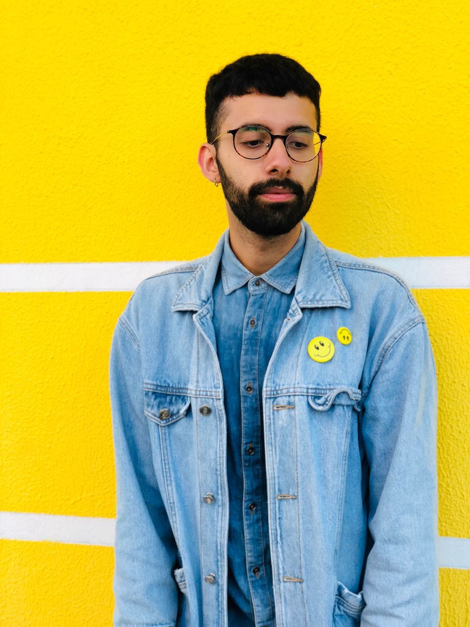 PORTRAIT OF YOUNG MAN STANDING BY YELLOW WALL