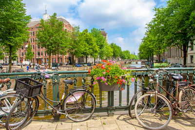 Bicycle by building against cloudy sky