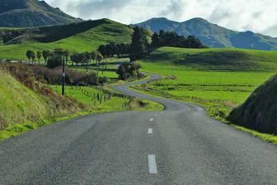 Road amidst field against sky