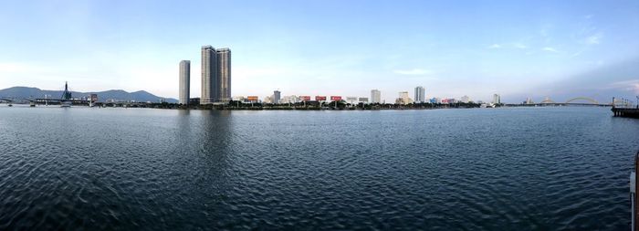 Sea by city buildings against sky