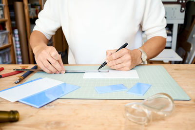 Midsection of man measuring tiles at table