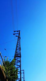 Low angle view of electricity pylon against clear blue sky