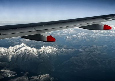 Airplane flying over snowcapped mountain against sky