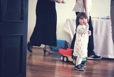 Cute baby girl by toy truck against women at restaurant