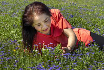 Rear view of woman with purple flowers on field