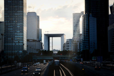 Vehicles on road amidst buildings in city against sky