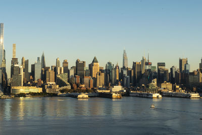 Sea by modern buildings against clear sky