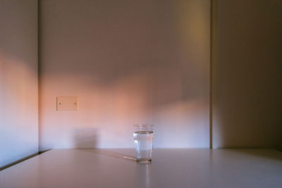 Empty glass on table against wall at home