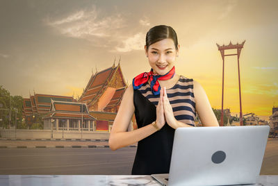 Portrait of smiling young woman standing against sky