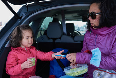 Mom and daughter having snacks in the back of an suv