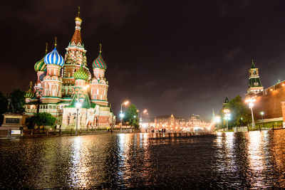 Illuminated saint basils cathedral by lake at night