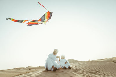 People sitting on land against clear sky