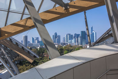 Low angle view of buildings against sky seen through glass window