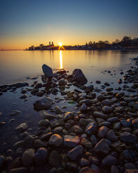 Rocks at beach against sky during sunset