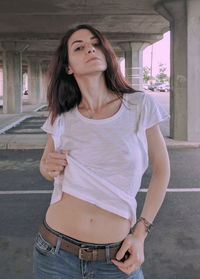 Portrait of woman holding top while standing at parking lot