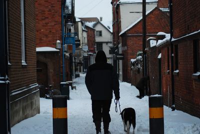 Rear view of man walking on street in city during winter