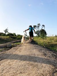 Full length of woman with dog on road