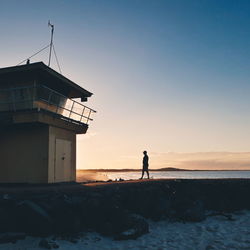 Silhouette people standing on beach against sky during sunset