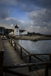 Traditional windmill by water against sky