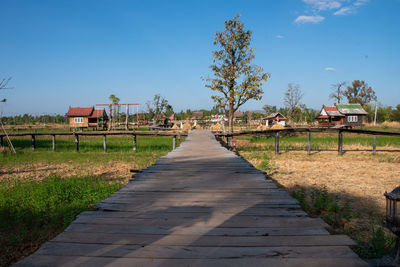 Footpath amidst buildings against blue sky